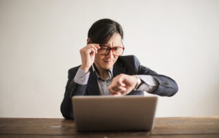 Confused businessman checking time on wristwatch