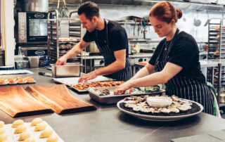 Man and woman wearing black and white striped aprons