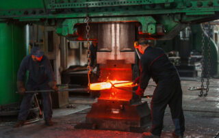 Two men holding two gray metal tools