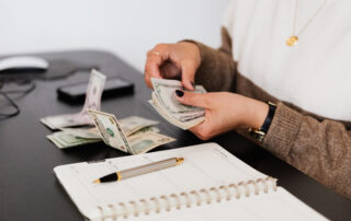 Crop payroll clerk counting money while sitting at table