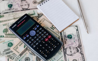 Calculator and notepad placed on usa dollars stack