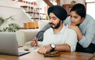 Cheerful couple counting with calculator and writing notes