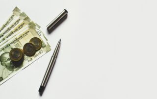 gray pen beside coins on Indian rupee banknotes