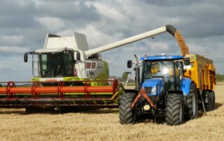 Blue tractor next to white farm vehicle at daytime