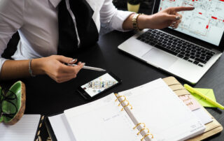 Person holding gray pen sitting near laptop