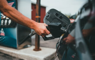 Person putting gasoline on a vehicle