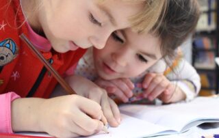 Girls on desk looking at notebook